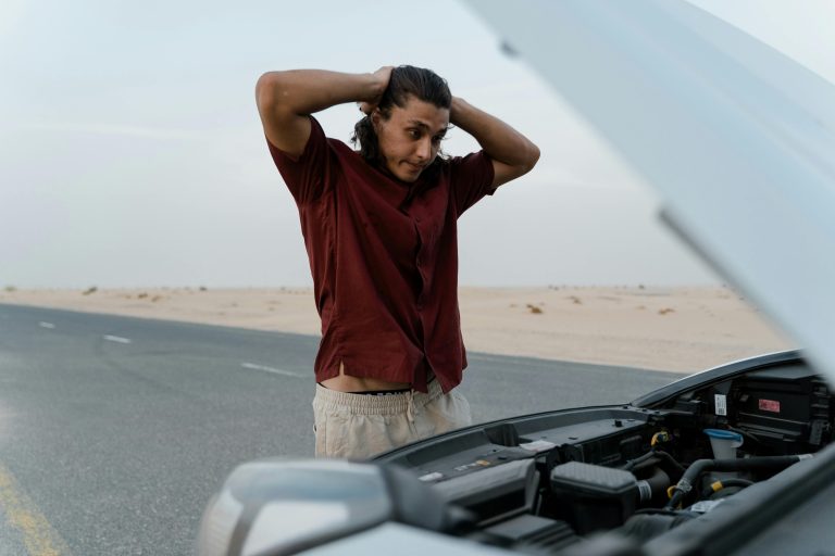 An upset man looking at his broken car